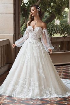 a woman in a white wedding dress standing on a tiled floor next to a tree