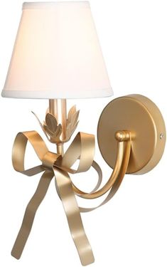 a gold wall light with a white shade on it's side and a golden ribbon around the lamp