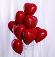 a bunch of red heart shaped balloons floating in the air