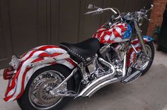 a red, white and blue motorcycle parked in front of a garage door with an american flag on it