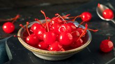 a bowl filled with cherries on top of a table