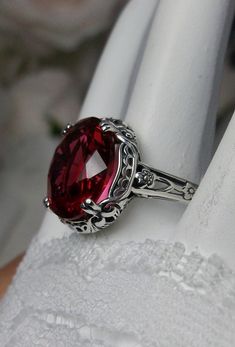 Simulated Ruby Edward Design#70 (smaller version) Custom Made Here we have an Edwardian reproduction ring in sterling silver filigree with a 5ct Red/Pink simulated ruby gemstone solitaire. The faceted oval gemstone gem is 12mm in length and 10mm in width. This ring also sits 7mm off the finger. The inside of the band is marked 925 for solid sterling. Notice the beautiful leaf design of the silver filigree setting and etched band. This is a lovely rendition of an Antique filigree ring; and it is Collectible Oval Ruby Ring In Silver, Ornate Round Ruby Ring In Sterling Silver, Victorian Sterling Silver Ruby Ring For Gift, Antique Oval Ruby Ring In Sterling Silver, Oval Ruby Ring With Intricate Design In Sterling Silver, Collectible Silver Ruby Ring, Engraved Sterling Silver Ruby Ring For Wedding, Star Ruby Ring, Antique Filigree