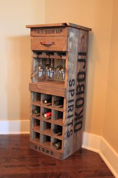 an old wooden crate with wine glasses in it sitting on a hard wood floor next to a wall