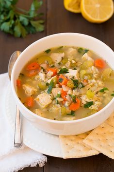 a white bowl filled with chicken and rice soup next to a slice of lemon wedge