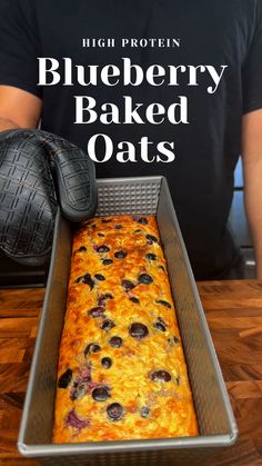 blueberry baked oats in a metal pan on a wooden table with a black glove