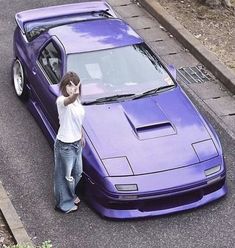 a woman leaning on the hood of a purple car