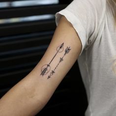 a woman's arm with an arrow tattoo on the left side of her arm