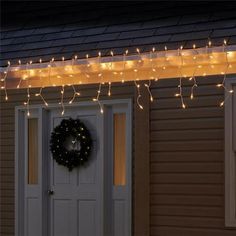 christmas lights are hanging over the front door of a house with a wreath on it