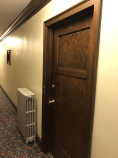 an empty hallway with a heater next to the door and a radiator