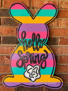 a wooden sign that says hello spring with an image of a bunny ears on it