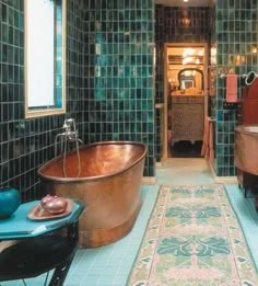 an old fashioned bathtub is in the middle of a bathroom with green tiles on the walls