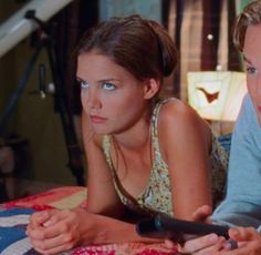 two people laying on a bed looking at something in front of the camera with one person holding a remote control