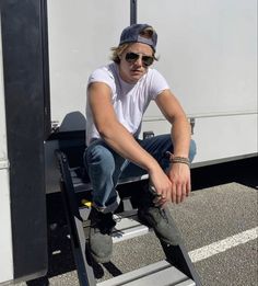 a man sitting on top of a metal step ladder next to a white trailer truck