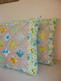 two decorative pillows sitting on top of a bed