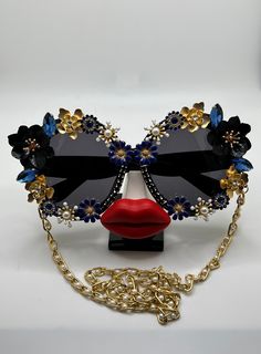 Bold, brilliant, and the most extra. Sparkling rhinestones and flowers surround these oversized, round lenses and are accompanied by an adjustable and removable eyewear chain. Featuring bold, fashion-forward designs, these glamorous sunglasses are perfect for making an entrance at any special occasion. Embellished and colorful, these fun and inspiring sunglasses will make sure you stand out in a crowd. Ideal for bachelorette parties, Vegas trips, weddings, birthdays, and more - Roaring Sunnies a Glamorous Sunglasses, Fancy Glasses, Eyewear Chain, Vegas Trip, Carnival Costumes, Bachelorette Parties