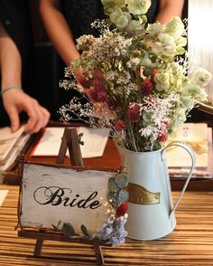 a vase filled with flowers sitting on top of a wooden table next to a sign