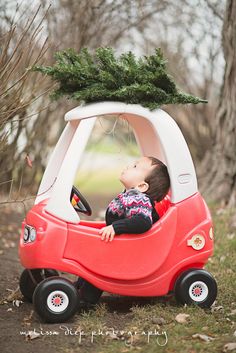 a small child in a red car with a christmas tree on top