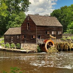 an old mill building on the side of a river with water coming out of it