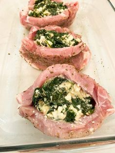 four slices of meat with spinach and cheese on them in a glass dish, ready to be cooked