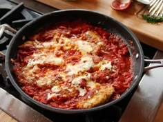 a skillet filled with sauce and cheese on top of a stove