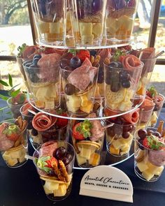 there are many desserts stacked on top of each other at the table with fruit in cups