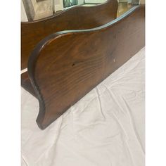 an old wooden bed frame sitting on top of a white sheet