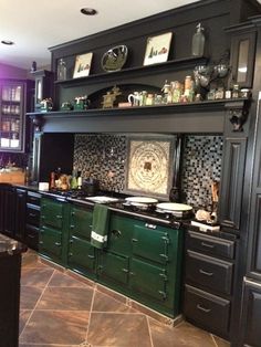 a kitchen with green cabinets and black counter tops in the center, along with tile flooring