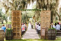 an outdoor ceremony with people sitting at the alter and standing in front of them, surrounded by mossy trees