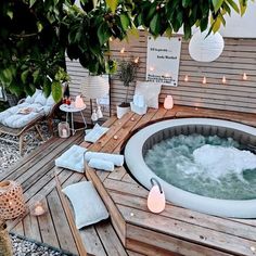 a hot tub sitting on top of a wooden deck next to a table with candles