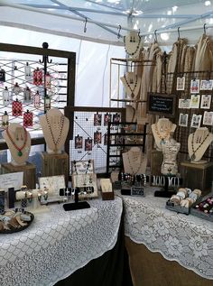 there are many necklaces on display in the store with lace tablecloth and doily