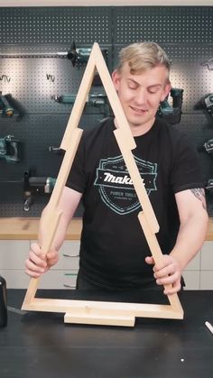 a man standing in front of a wooden triangle