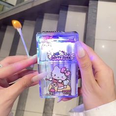 a person holding a hello kitty toothbrush in a plastic container with an ice cream stick sticking out of it