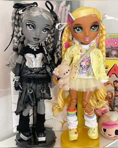 two dolls standing next to each other on a shelf