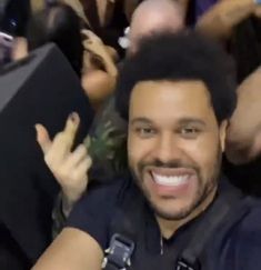 a man with an afro is taking a selfie in front of a group of people