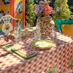 the table is set with plates, silverware and flowers in vases on it