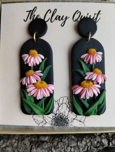 the clay quiit is decorated with pink and yellow flowers on black oval shaped earrings