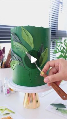 someone is decorating a green cake with leaves