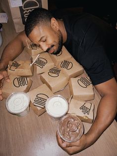 a man sitting at a table with several boxes and cups in front of his face