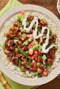 a white plate topped with rice, meat and veggies next to a fork