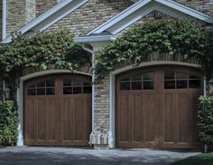 two brown garage doors in front of a brick building with ivy growing on the windows