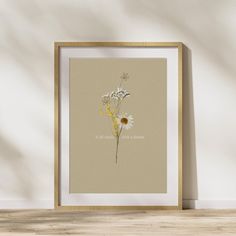 a white and yellow flower on a beige background in a wooden frame against a wall