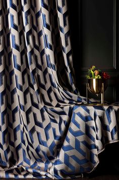 a blue and white blanket sitting on top of a table next to a vase with flowers