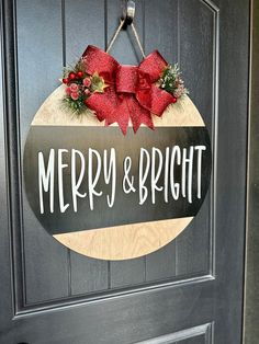 a merry and bright sign hanging on the front door to a house with red bows