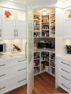 a kitchen with white cabinets and lots of cupboard space in the corner between two walls