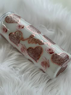 a pink and white canister with hearts on it sitting on a fluffy white surface