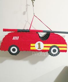 a red firetruck hanging from the side of a wall in front of a white wall