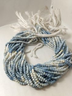 a white and blue beaded necklace with tassels