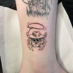 a crab tattoo on the ankle with an angel above it and a devil in the background