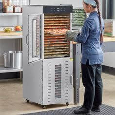 a woman standing in front of an oven with food on it's rack and holding the door open