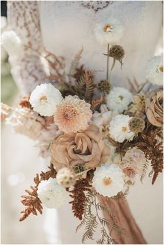 a bridal holding a bouquet of flowers in her hands and wearing a wedding dress